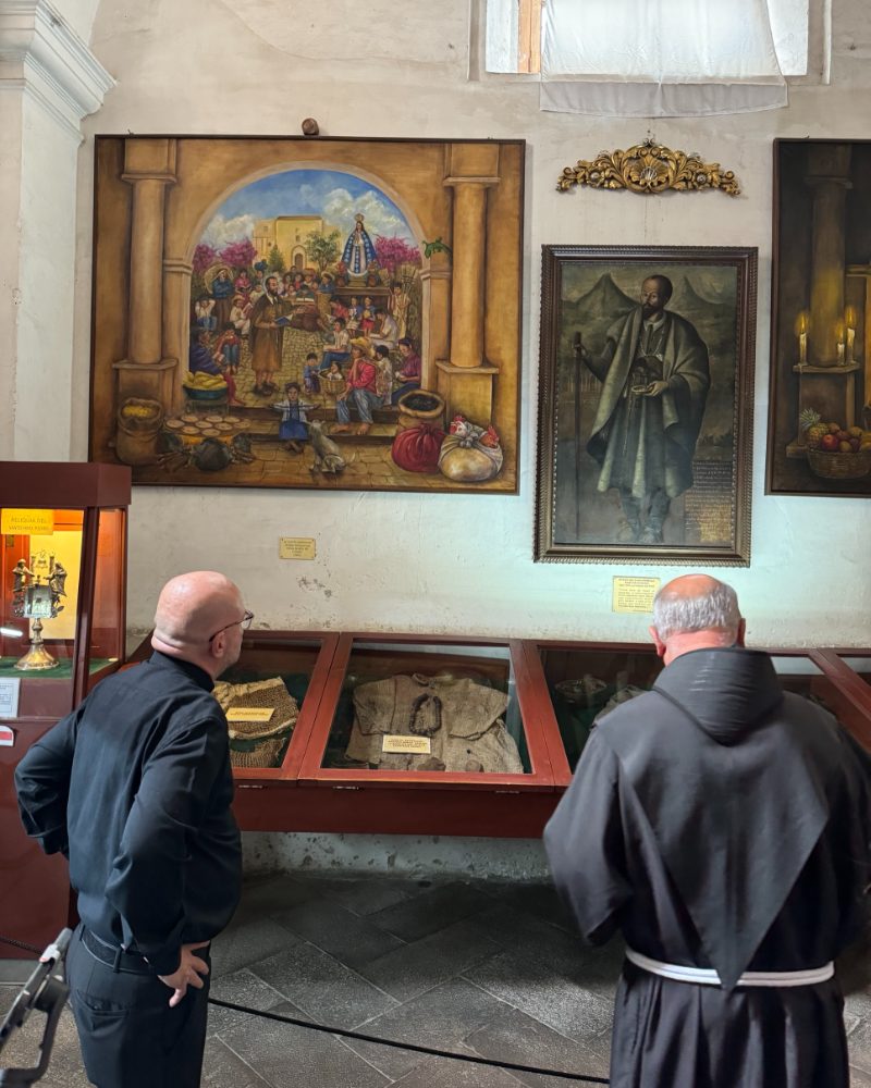 Fray Edwin, con hábito franciscano, y el padre Iñigo López miran las vitrinas del museo del Santo Hermano Pedro