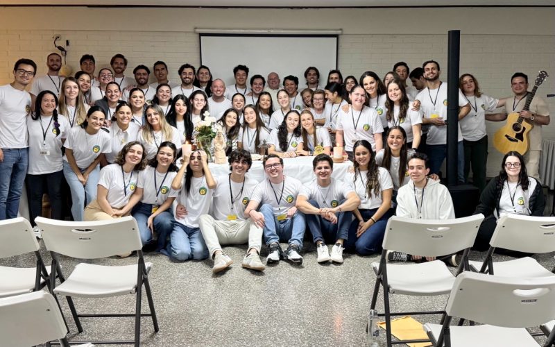Jóvenes adultos del retiro Magnificat, con camisetas blancas, reunidos alrededor del altar
